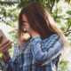 Image of a girl looking at her smartphone while covering her face with her other hand