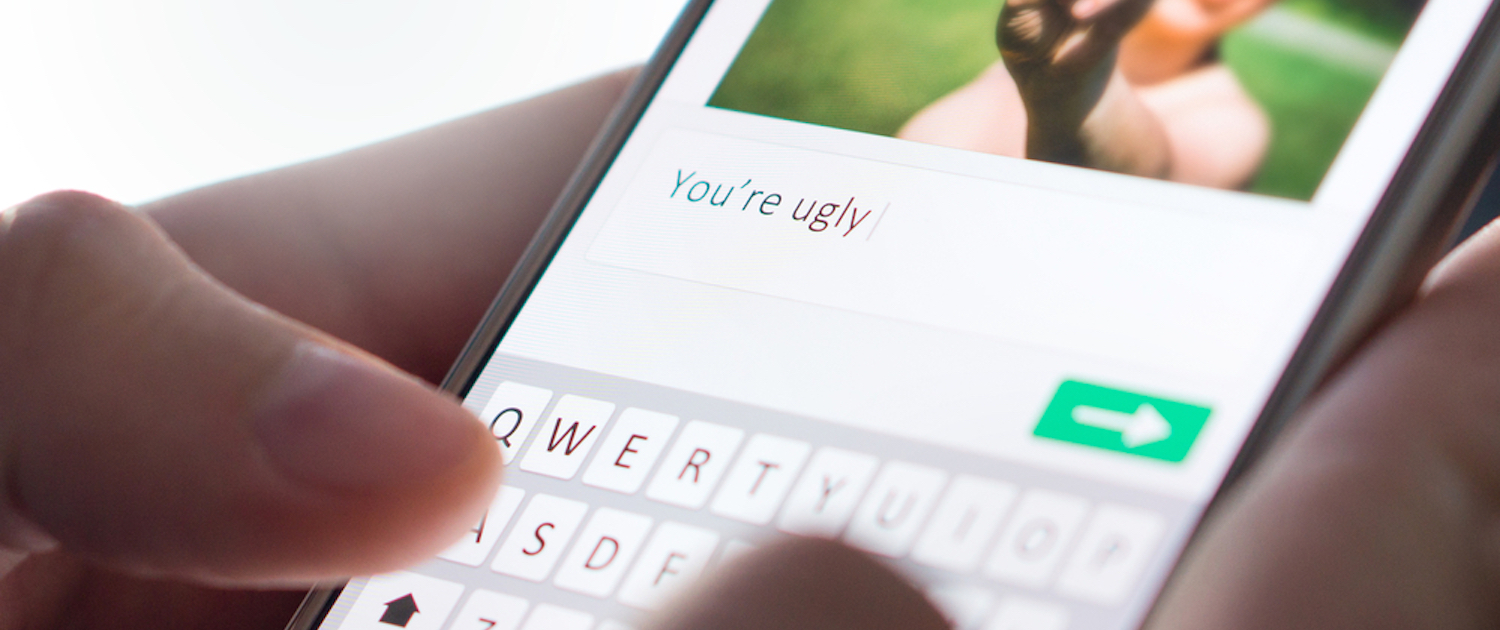 Image of hands commenting on someone's picture "You're uugly" on their smartphones and are about the send the message