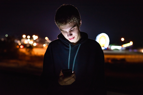 Image of a young teen boy looking at his mobile phone in the evening